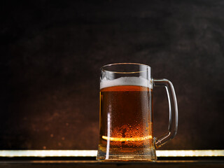Light beer mug on a dark background. Back light, copy space