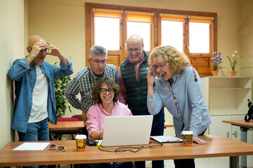 Senior friends learning to use a laptop together