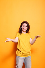 Joyful young woman with expressive positive attitude welcoming with raised arms in studio. Portrait...
