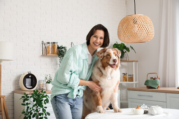 Pretty young woman with cute Australian Shepherd dog on table in kitchen