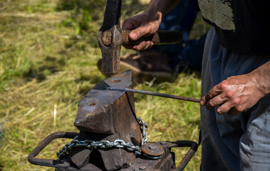 Blacksmith shapes the metal by striking the anvil with a hammer. Ancient craft