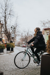 A young woman enjoys a leisurely bike ride on a vintage bicycle along a picturesque cobblestone street in an urban setting.