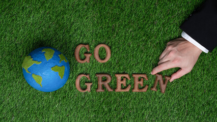 Message Go Green letter with planet Earth icon or symbol arranged by businessman hand to promote...