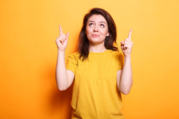 Confident brunette woman in professional fashion, gesturing with sign language on isolated background. Her happy expression and upward gaze conveys her expertise and emotion.
