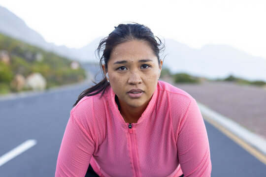 Biracial female hiker resting during an adventure run, surrounded by nature, copy space