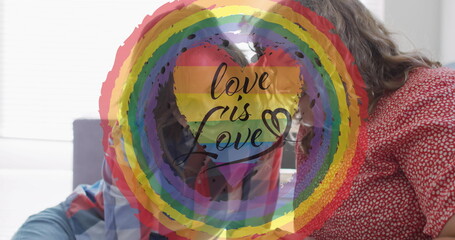 Caucasian couple holding sign with a rainbow and love is love
