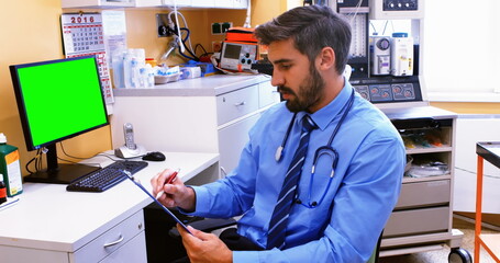 Caucasian male doctor wearing blue scrubs reviewing document
