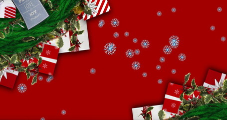 Festive scene: Red background, snowflakes, gift cards, greenery, decorations