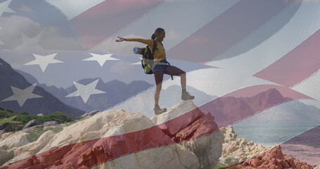 Biracial woman on rock with American flag. - 788804727