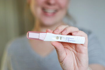 Close up of a happy woman holding a positive pregnancy test