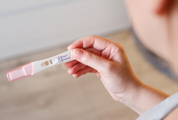 Close up top view of a woman holding a positive pregnancy test