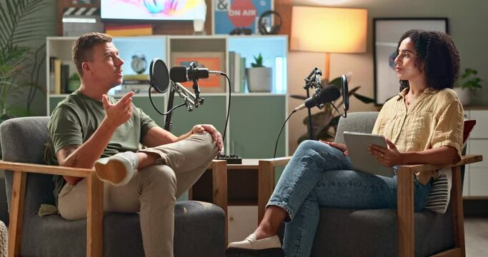 Happy people, interview and podcast with conversation in meeting for discussion or career news at studio. Man and woman talking on air together with mic for communication, live chat or recording