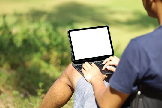 white blank screen of laptop outdoors, man in casual clothes working remotely, generation z concept working in nature.