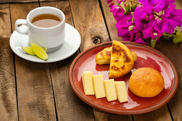 Colombian food - Arepa boyacense for breakfast, accompanied with cheese, almojabana and aguapanela with lemon