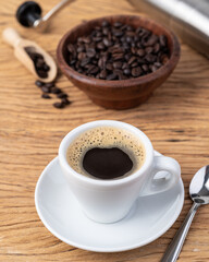 Coffee in a cup with beansand grinder over wooden table
