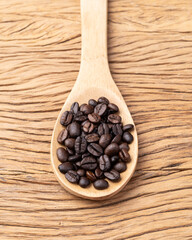 Coffee beans on a spoon over wooden table