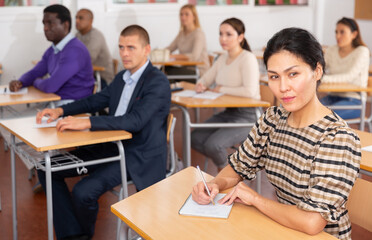 Portrait of confident woman sitting in class working during group business training