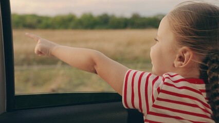 Happy family travels by car. Little girl kid enjoys family trip by car. Child, stretching his hand out of car window, laughs. Girl child looks out of car window. Child holiday emotion. Family vacation