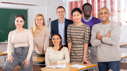 Portrait of multinational group of smiling adult people posing together in classroom. Concept of...