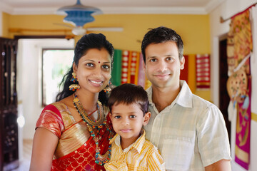 Traditional family portrait with couple posing with their little son at home, woman wearing traditional clothes