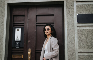 A chic young girl with sunglasses strolls through the city streets on an autumn day, reflecting a casual urban teenage lifestyle.