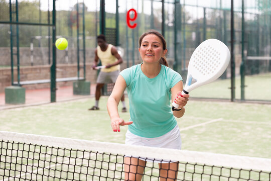 Portrait of cheerful woman paddle tennis player during friendly doubles couple match with male friend at court