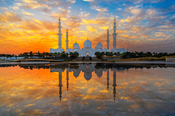 The Sheikh Zayed Grand Mosque, the largest mosque in the UAE under a colorful orange sunset...