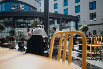 Two business professionals engaged in a discussion at a city cafe with modern architecture in the background.