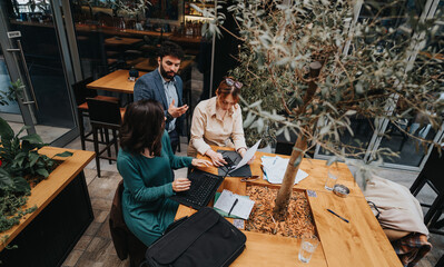 Startup colleagues collaborate over coffee, discussing business strategies and ideas at a casual meeting in an urban cafe.