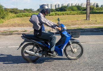 A motorcyclist rides a scooter with a fluttering jacket