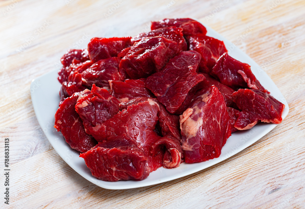 Wall mural diced of fresh raw veal fillet prepared for stew cooking on wooden background..