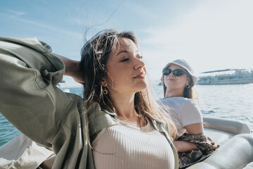 Two young women soaking up the sun and enjoying a breezy boat ride on the sea, displaying casual chic and relaxation.