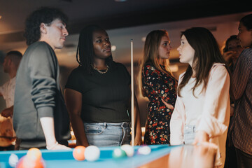 Group of diverse friends gathered around a billiard table, enjoying a fun night out in a lively bar atmosphere, depicting happiness and togetherness.