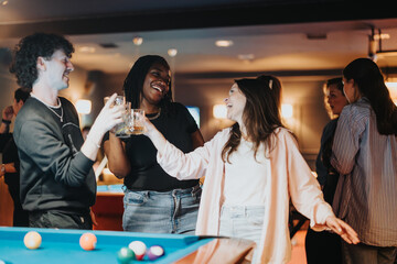 A joyful group of friends laughing and having fun during a night out at a bar with a billiards table.