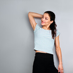 Beautiful young happy casual woman thinking and looking up on blue studio background on empty copy space. Closeup