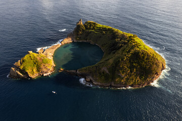 Picturesque volcanic islet in wavy ocean on sunny day