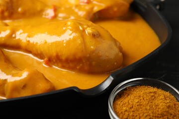Tasty chicken curry and spice on black table, closeup