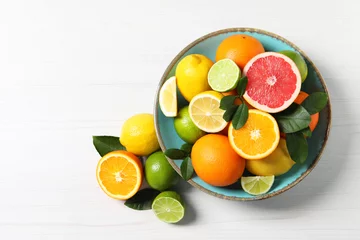 Schilderijen op glas Different cut and whole citrus fruits on white wooden table, top view. Space for text © New Africa