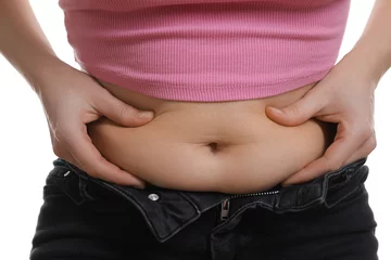 Deurstickers Woman touching belly fat on white background, closeup. Overweight problem © New Africa
