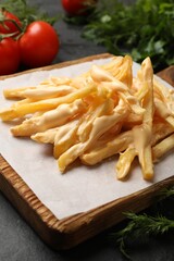 Delicious French fries with cheese sauce, tomatoes and dill on black table, closeup