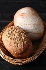 Gordijnen Wicker basket with fresh bread on black wooden table, closeup © New Africa