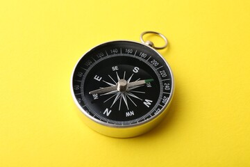 One compass on yellow background, closeup. Tourist equipment