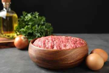 Gordijnen Raw ground meat in bowl and different products on grey table © New Africa