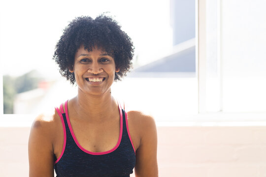 Biracial yoga instructor in studio wearing tank top is smiling, copy space