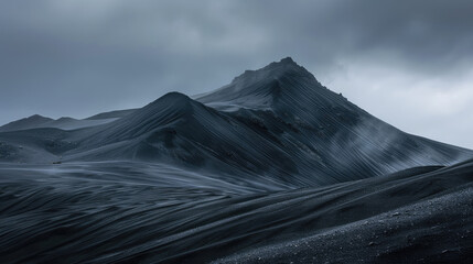 Monochrome majesty of black sand dunes rise to fill the expanse of cloudy clouds