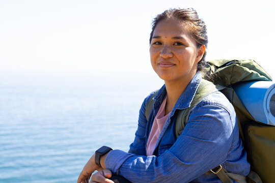 Biracial female hiker resting by sea, copy space, adventure in nature