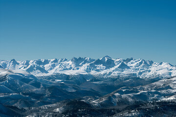 Fototapeta na wymiar Breathtaking Winter Panoramic View: Majestic Snow-Covered Peaks of Pyrenees Mountains under Pristine Blue Sky