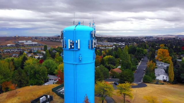 Aerial Panning Shot Of Blue Standpipe Water Storage Tank On Hill During Autumn Season Under Clouds - Rural, Idaho