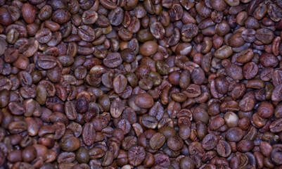 Close-up view of coffee beans being manually dried in the sun