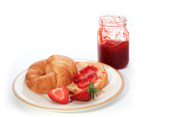two butter crescent rolls on a plate with a mason jar of home made jam isolated on white
